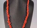 un collier composé de perles de corail, présenté sur un mannequin noir