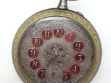 montre de poche sur fond blanc, avec des chiffres rouges sur le cadran