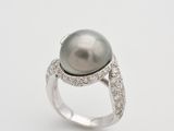 a black pearl and diamond ring on a white background