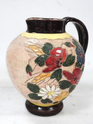un vase avec des fleurs peintes dessus, posé sur une table