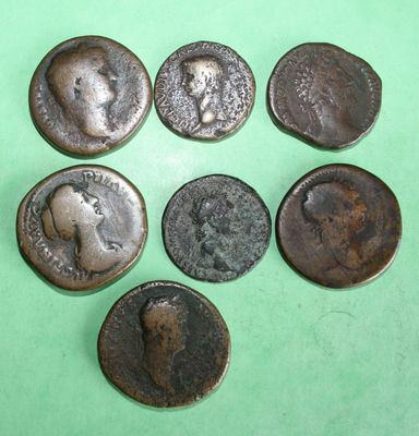 six ancient roman coins on a green surface
