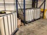 Deux grands conteneurs blancs sont posés sur des palettes dans un entrepôt.