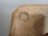 a brown vase with a stamp on it sitting on a table