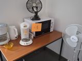 une petite table sur laquelle se trouvent un ventilateur et un micro-ondes