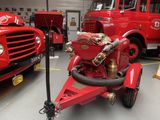 a red fire truck with a hose attached to it ' s side