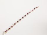 a close up of a bracelet with a red stone on it
