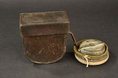 an old leather case with a small metal object in it on a black surface