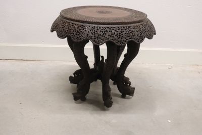 a small wooden table with a carved top on the floor