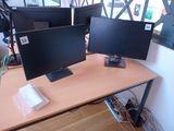 two computer monitors sitting on top of a wooden desk