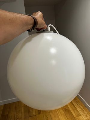 une personne tenant un grand ballon blanc dans une pièce