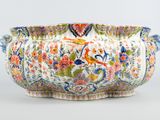 a close up of a vase with a bird and flowers on it