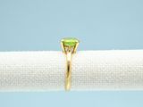 a close up of a ring with a green stone on top of a white cloth