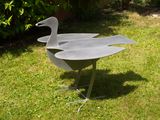 a metal bird that is standing in the grass