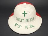 an old white fireman ' s hat with a green cross on it
