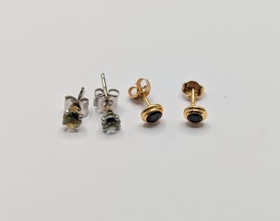 three pairs of gold and silver stud earrings on a white surface