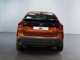 the rear end of an orange car parked in a white room