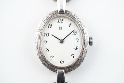 une montre en argent avec une chaîne autour d'elle sur une surface blanche