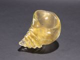 an image of a yellow glass sculpture of a shell on a black surface