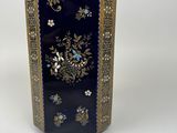 a blue vase with gold trim and flowers on it
