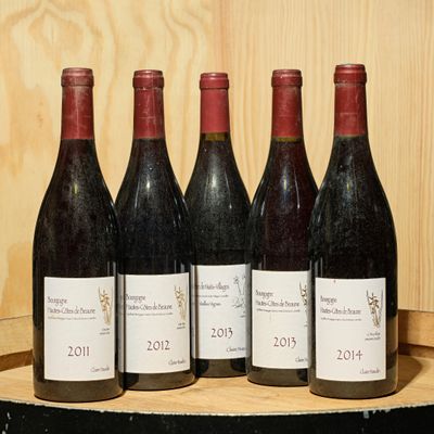 six bottles of wine are lined up on a wooden barrel