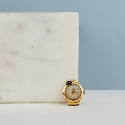 un bloc de marbre blanc sur lequel repose une montre en or