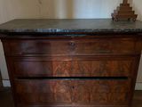 a wooden dresser with a marble top and a lamp on top