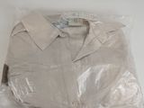 une chemise blanche emballée dans du plastique, posée sur une table