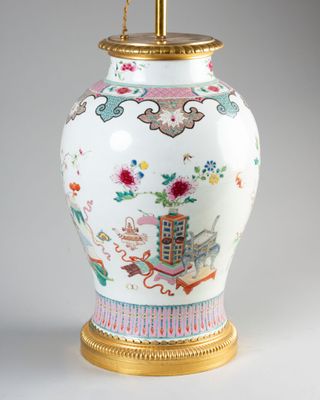 un vase blanc avec un socle doré sur lequel est posée une lampe