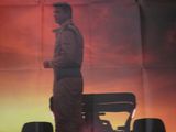 une image représentant une affiche sur laquelle figure un homme debout devant une voiture de course