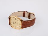 an image of a gold watch with brown leather strap