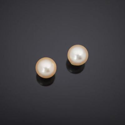 a pair of pearl earrings on a black surface