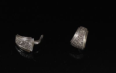 une paire de boucles d'oreilles en argent posées sur une surface noire