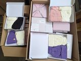 Plusieurs cartons contenant des bonnets et des écharpes tricotés sont empilés les uns sur les autres
