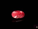 a close up of a red ruby stone on a black surface