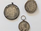 trois pièces d'argent et un porte-clés en argent posés sur une surface blanche