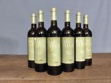 six bottles of wine are lined up on a wooden table