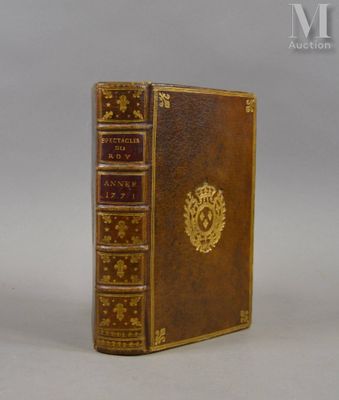 un livre marron aux tranches dorées posé sur une surface blanche