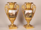 paire de vases en or avec, en arrière-plan, une peinture représentant un château