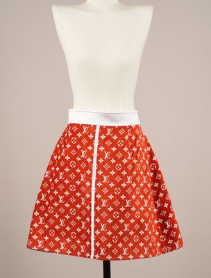 La jupe est confectionnée dans un tissu à imprimé Louis Vuitton orange et blanc.