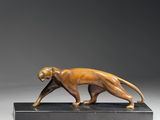 une sculpture en bronze représentant un chat, posée sur un socle noir
