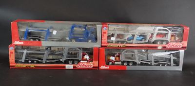 Trois camions miniatures dans leur emballage sont alignés sur une surface noire
