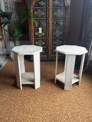 two white side tables sitting on top of a carpeted floor