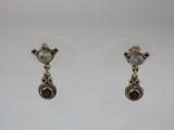 a pair of silver earrings with garnets on them