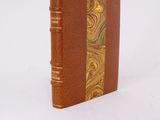 an old book with a brown cover sitting on top of a white surface