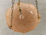 a pink glass bowl hanging from a chain