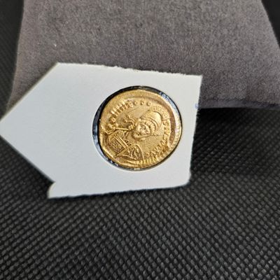 une vieille pièce d'or posée sur un oreiller, à côté d'un autre oreiller