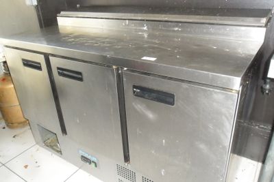 un plan de travail en acier inoxydable dans une cuisine équipée de deux réfrigérateurs