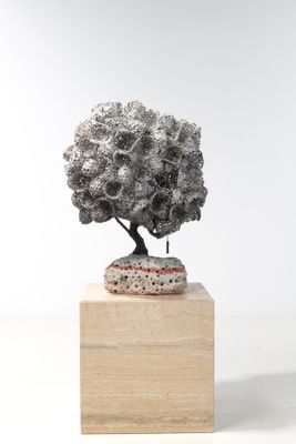 une sculpture représentant un arbre posée sur un bloc de bois