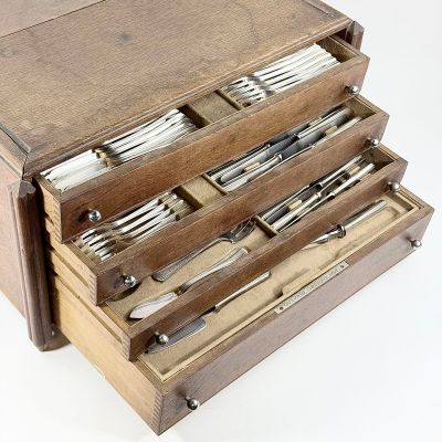une boîte en bois contenant de l'argenterie sur une surface blanche