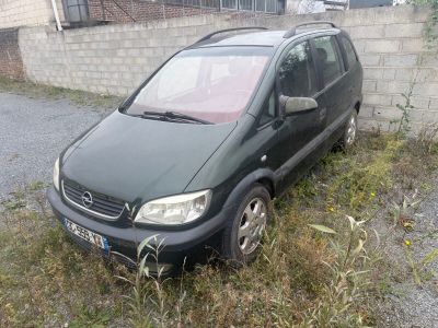 une petite voiture noire garée dans l'herbe près d'un mur de briques